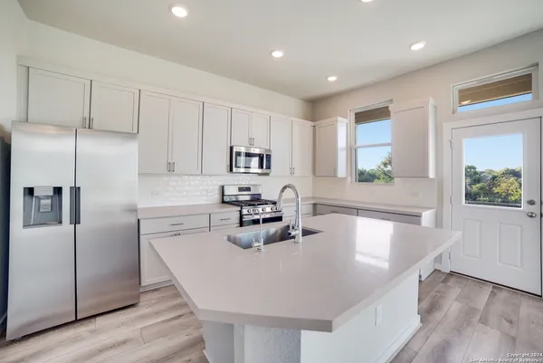a kitchen with granite countertop a sink a center island stainless steel appliances and cabinets