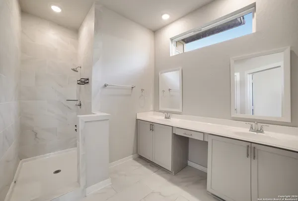 a bathroom with a double vanity sink mirror and shower