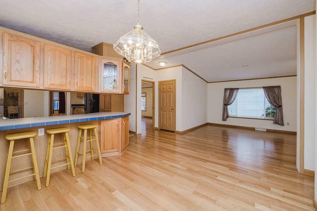 18 Mockingbird Lane Tiverton, RI 02878 - Photo 5 of 32 a view of an empty room with wooden floor and a kitchen