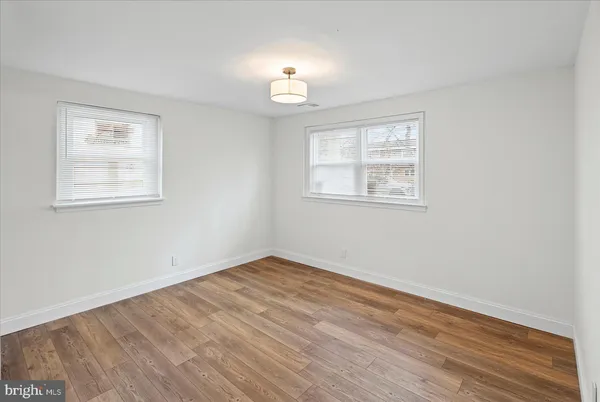 an empty room with wooden floor chandelier fan and windows