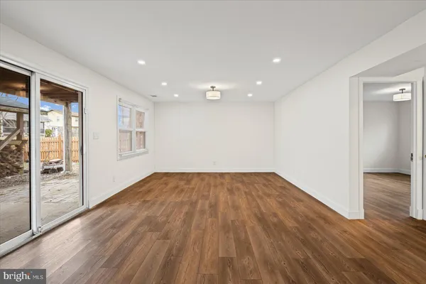 a view of an empty room with wooden floor and windows