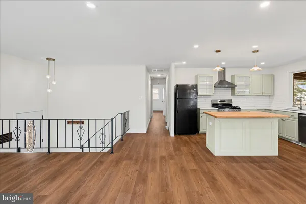 a view of kitchen with stainless steel appliances granite countertop a stove a refrigerator a sink and a wooden floors