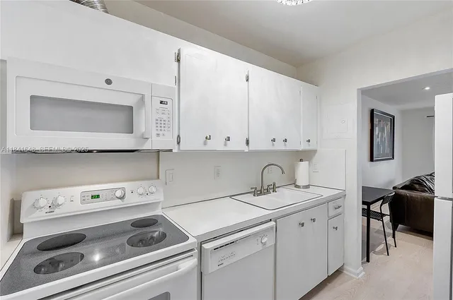 a view of cabinets a sink and a stove sitting inside of a kitchen