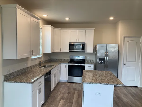 a kitchen with stainless steel appliances granite countertop a stove top oven a sink and a refrigerator