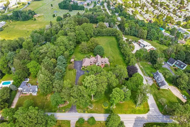 an aerial view of residential house with outdoor space and trees all around
