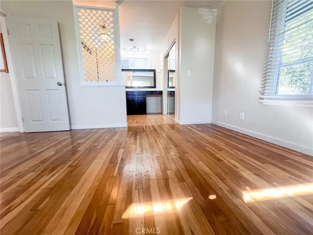 a view of kitchen and empty room with wooden floor
