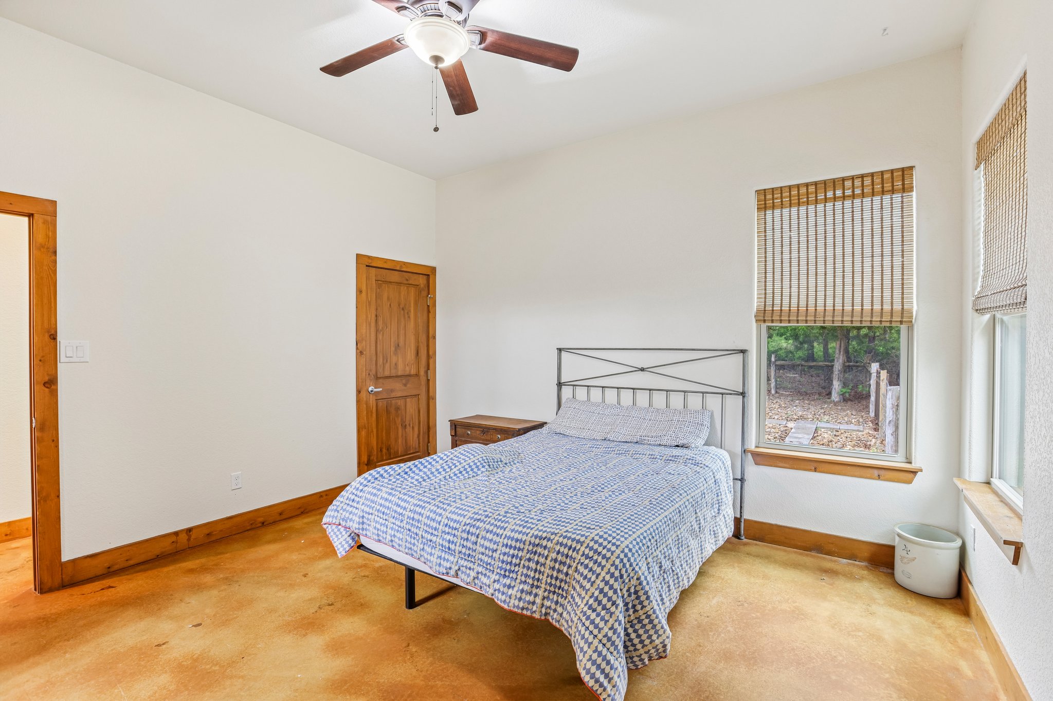 267 Corral Road Smithville, TX 78957 - Photo 21 of 40 Bright room featuring a ceiling fan, exposed wood trim, a tall window with bamboo blinds, and a wood-finish floor