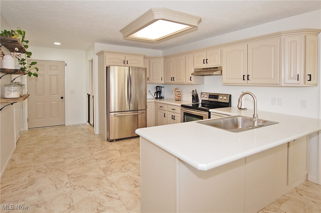 26875 W Road Wellington, OH 44090 - Photo 3 of 26 Kitchen with sink, appliances with stainless steel finishes, kitchen peninsula, and a textured ceiling