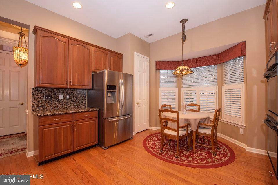 110 Wild Dunes Way Jackson, NJ 08527 - Photo 34 of 82 a kitchen with stainless steel appliances granite countertop a refrigerator a stove and a dining table with wooden floor