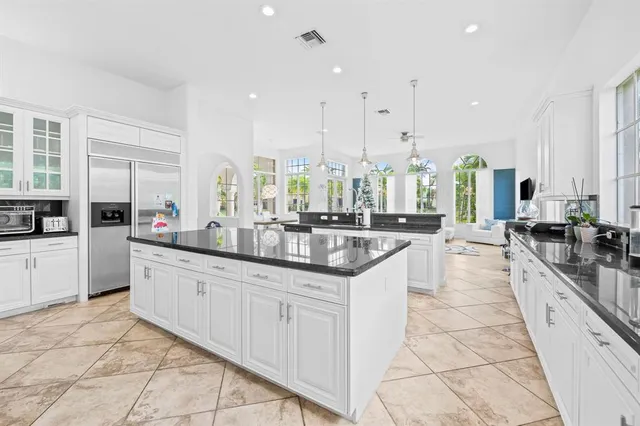 a large white kitchen with granite countertop a sink and cabinets