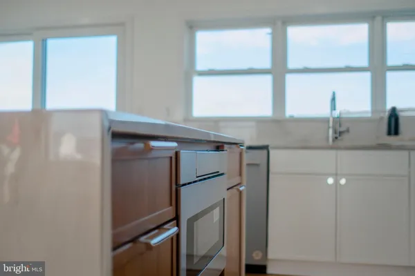 a kitchen with stainless steel appliances granite countertop a refrigerator a sink a stove and white cabinets with wooden floor
