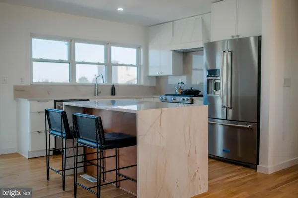 a kitchen with stainless steel appliances kitchen island granite countertop a refrigerator and a stove top oven