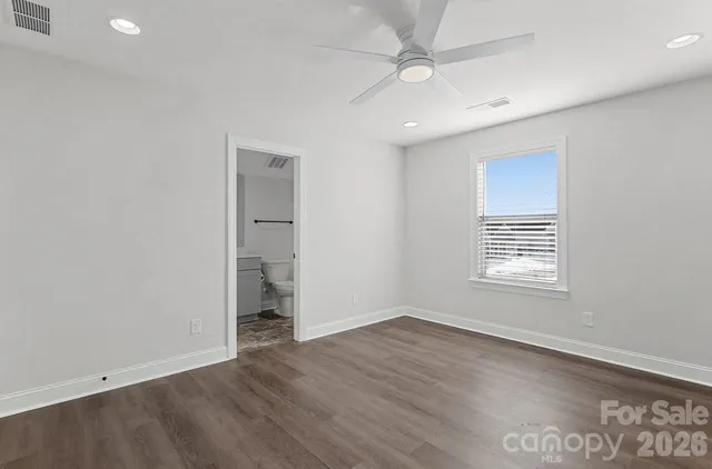 an empty room with wooden floor closet and windows