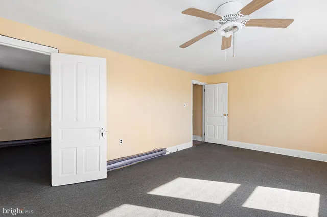 an empty room with closet and a ceiling fan