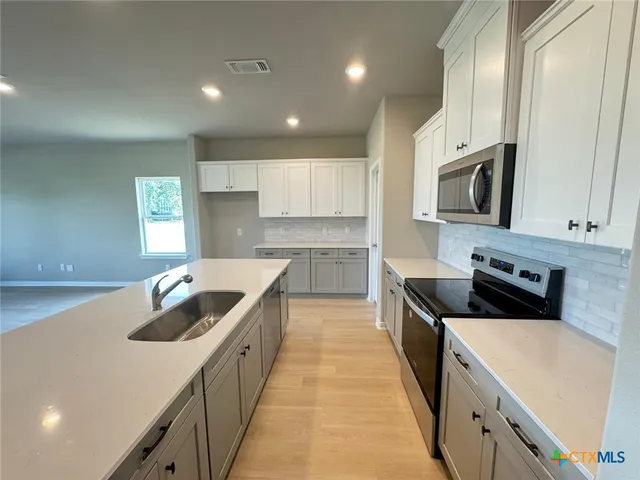 a kitchen with kitchen island granite countertop a sink and stove top oven