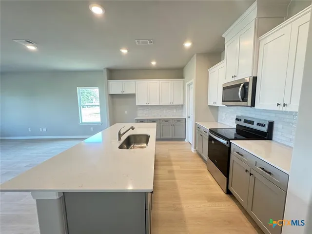 a kitchen with a sink a stove top oven and white kitchen