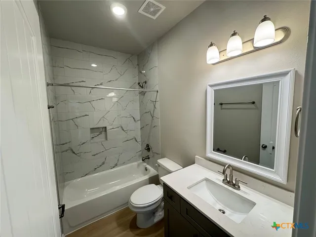 a bathroom with a bathtub shower sink mirror and toilet