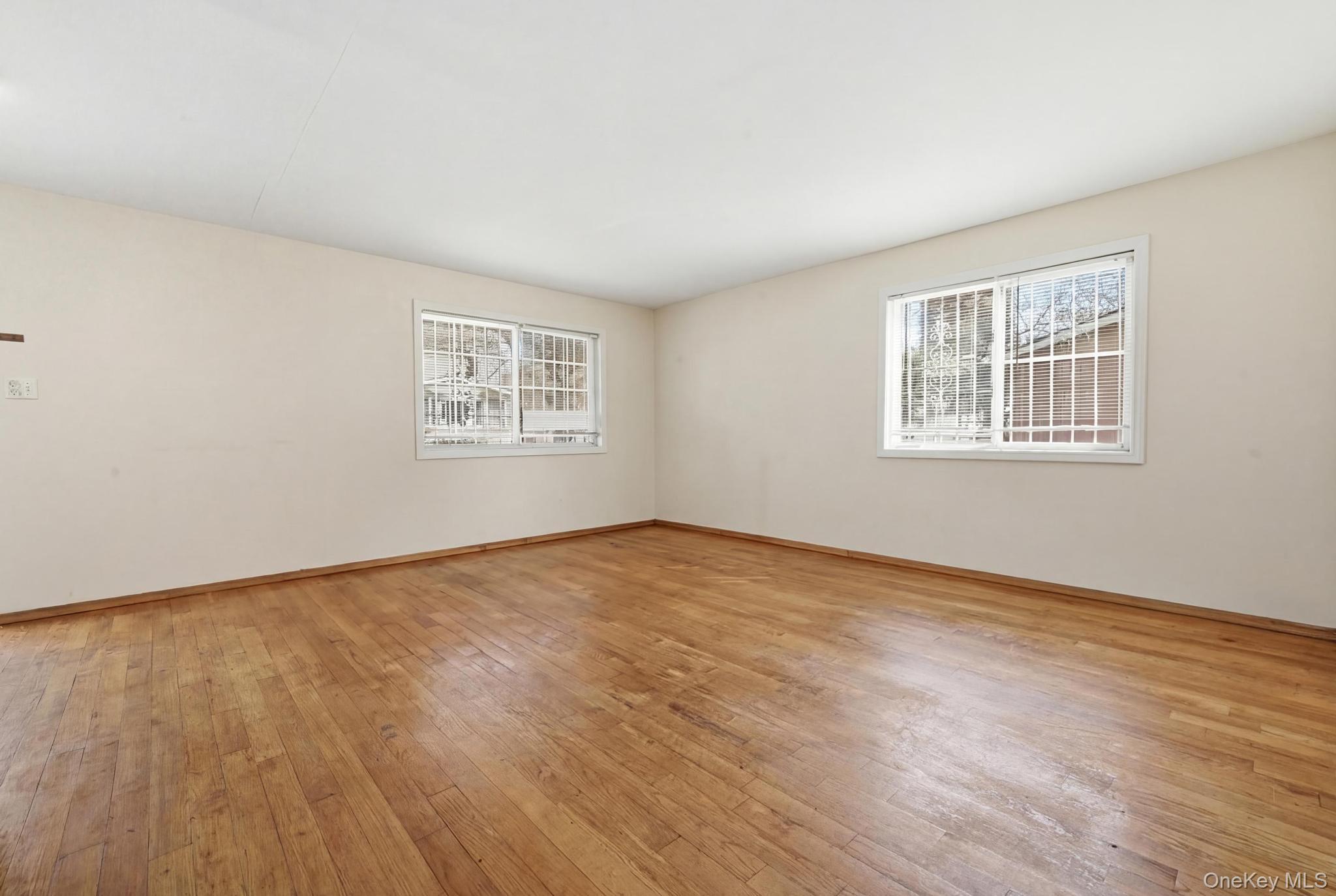 61-16 161 Street Queens, NY 11365 - Photo 8 of 22 an empty room with wooden floor and windows