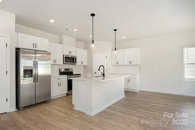 a large kitchen with stainless steel appliances sink a microwave and cabinets