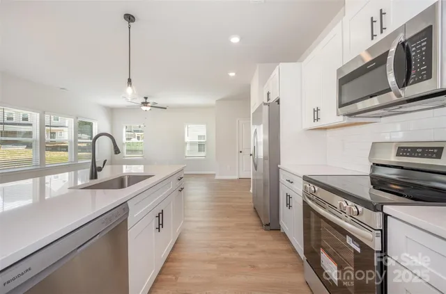 a kitchen with stainless steel appliances granite countertop a sink and dishwasher a stove top oven with wooden floor