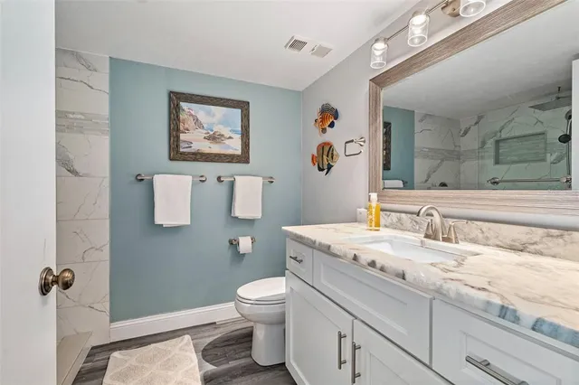 a bathroom with a granite countertop sink mirror vanity and toilet