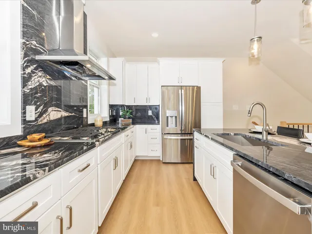 a large kitchen with stainless steel appliances granite countertop a sink and a refrigerator