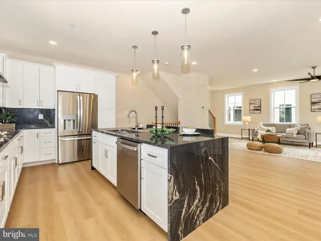 a kitchen with a refrigerator a stove top oven a sink dishwasher and white cabinets with wooden floor