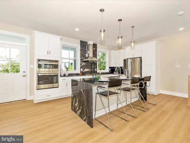 a view of a kitchen with kitchen island stainless steel appliances refrigerator stove microwave and white cabinets