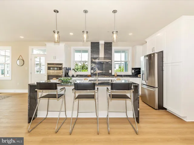 a kitchen with stainless steel appliances kitchen island granite countertop a refrigerator a stove a kitchen island with a dining table and chairs