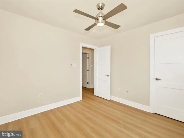 an empty room with wooden floor and ceiling fan