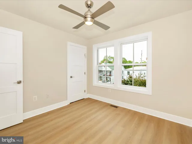 an empty room with wooden floor fan and windows
