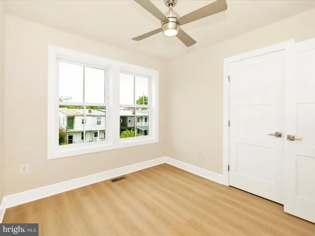 an empty room with wooden floor fan and windows