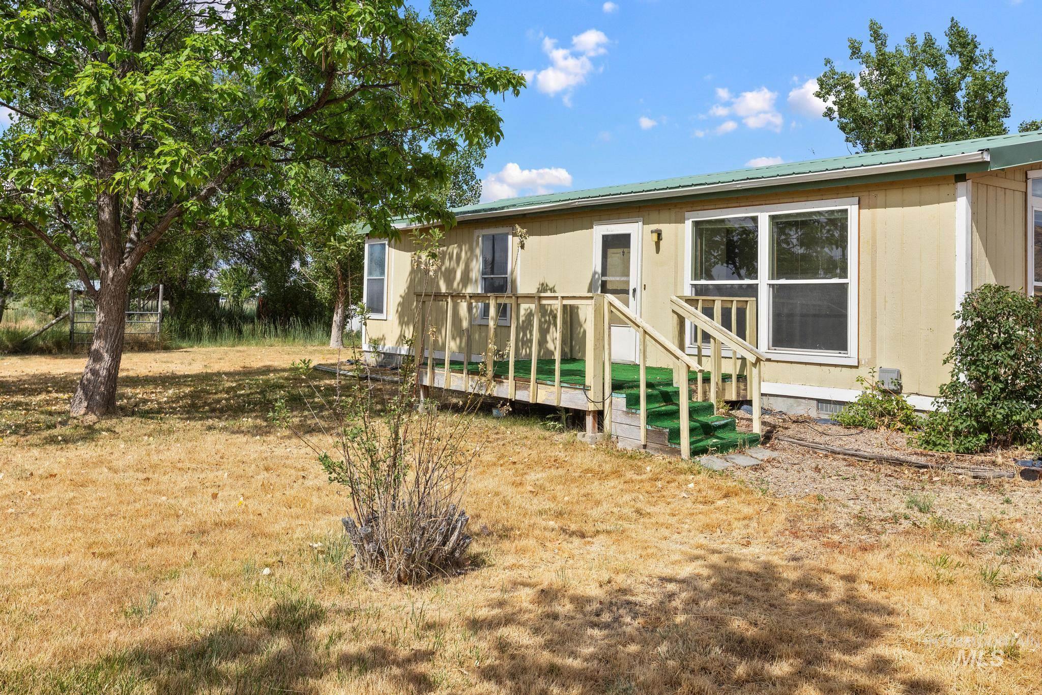 3680 South Mill Road Emmett, ID 83617 - Photo 5 of 38 Exterior view featuring a light yellow siding, green metal roof, and a wooden deck with steps