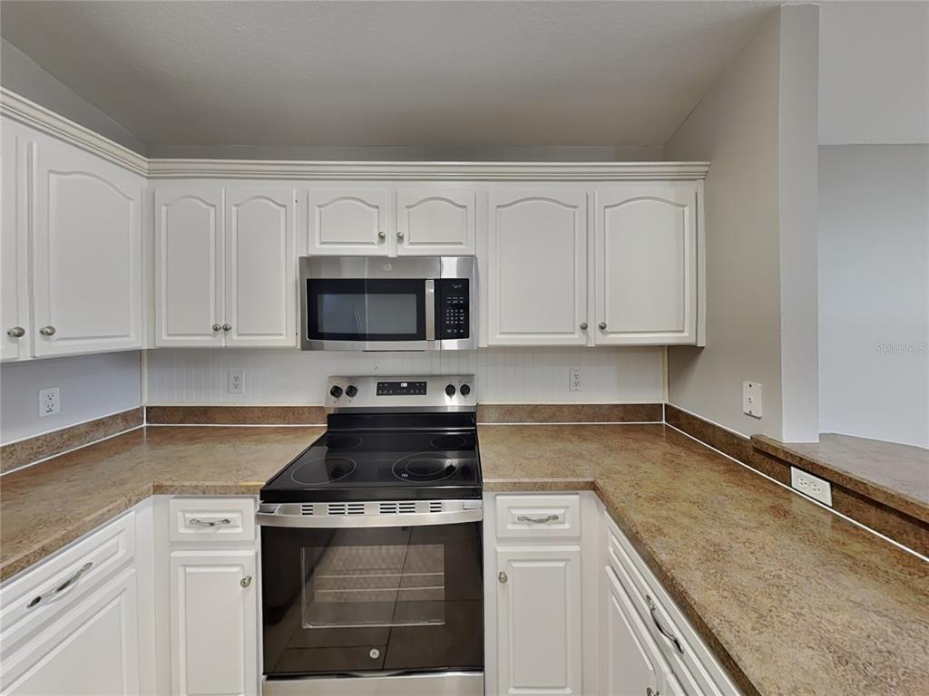 Undisclosed Address Port Orange, FL 32127 - Photo 6 of 16 a kitchen with granite countertop white cabinets and stainless steel appliances