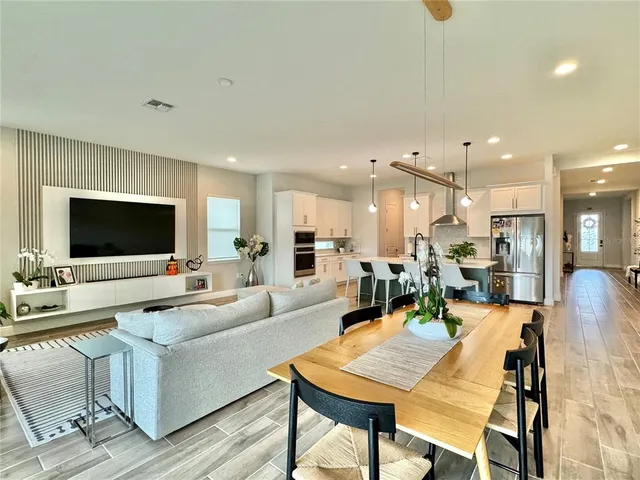 a kitchen with stainless steel appliances kitchen island granite countertop a dining table chairs sink and white cabinets
