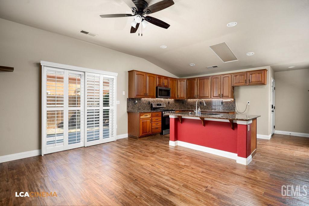 Undisclosed Address Bakersfield, CA 93312 - Photo 21 of 28 a kitchen with stainless steel appliances kitchen island granite countertop a refrigerator a stove top oven a sink with wooden floor and cabinets