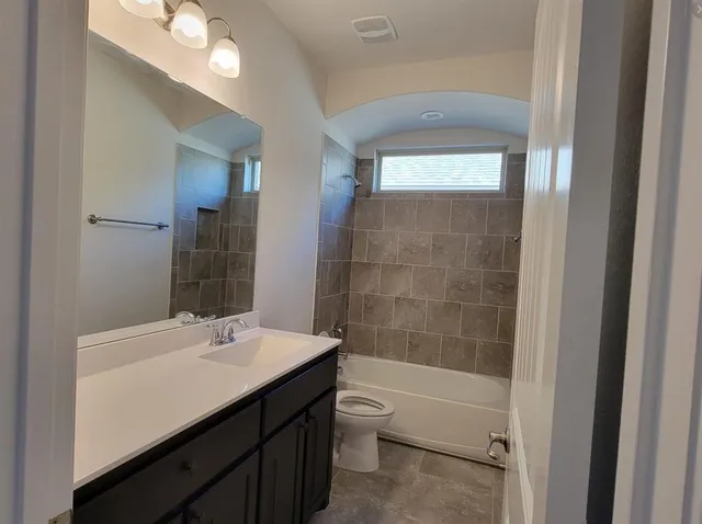 a bathroom with a bathtub shower sink vanity and toilet