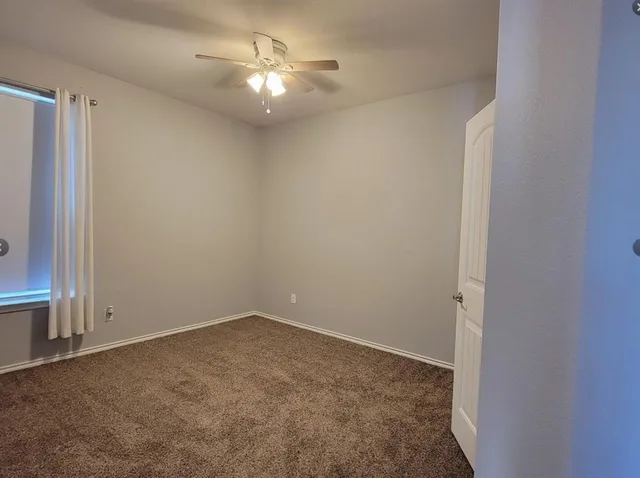 an empty room with a ceiling fan and a window