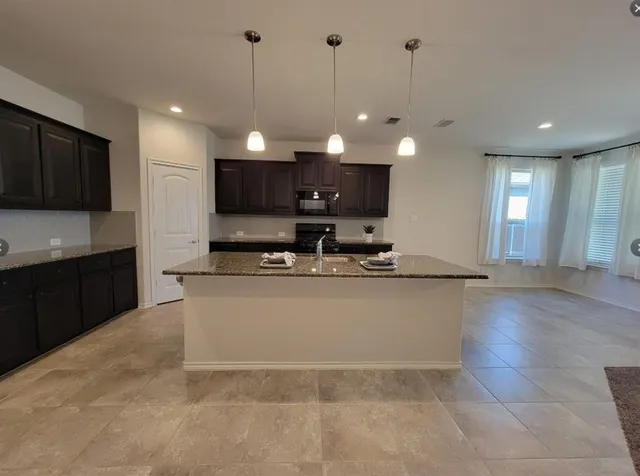 a large kitchen with kitchen island a sink dishwasher a refrigerator and a fireplace