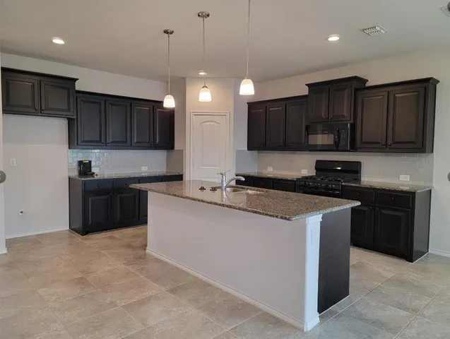 a kitchen with stainless steel appliances granite countertop a sink a stove a microwave and a refrigerator
