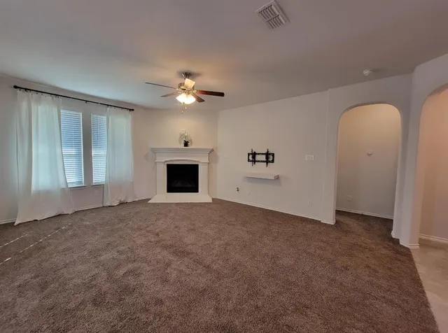 an empty room with windows and fireplace