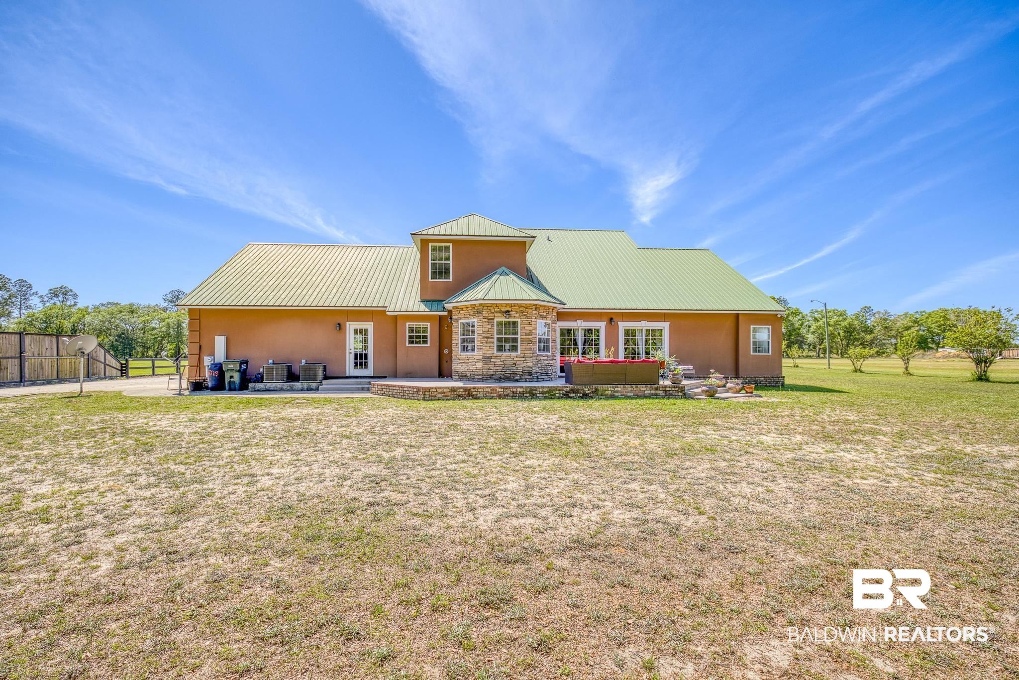 32875 Faircloth Road Lillian, AL 36549 - Photo 57 of 85 Rear view of property with a patio area, stone siding, and a standing seam roof