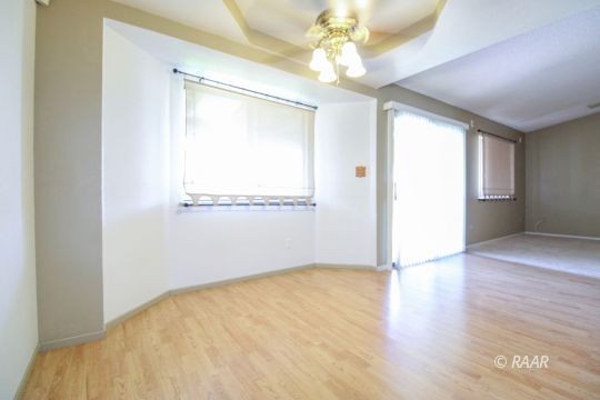 636 Heather Court Ridgecrest, CA 93555 - Photo 15 of 33 an empty room with wooden floor chandelier fan and windows