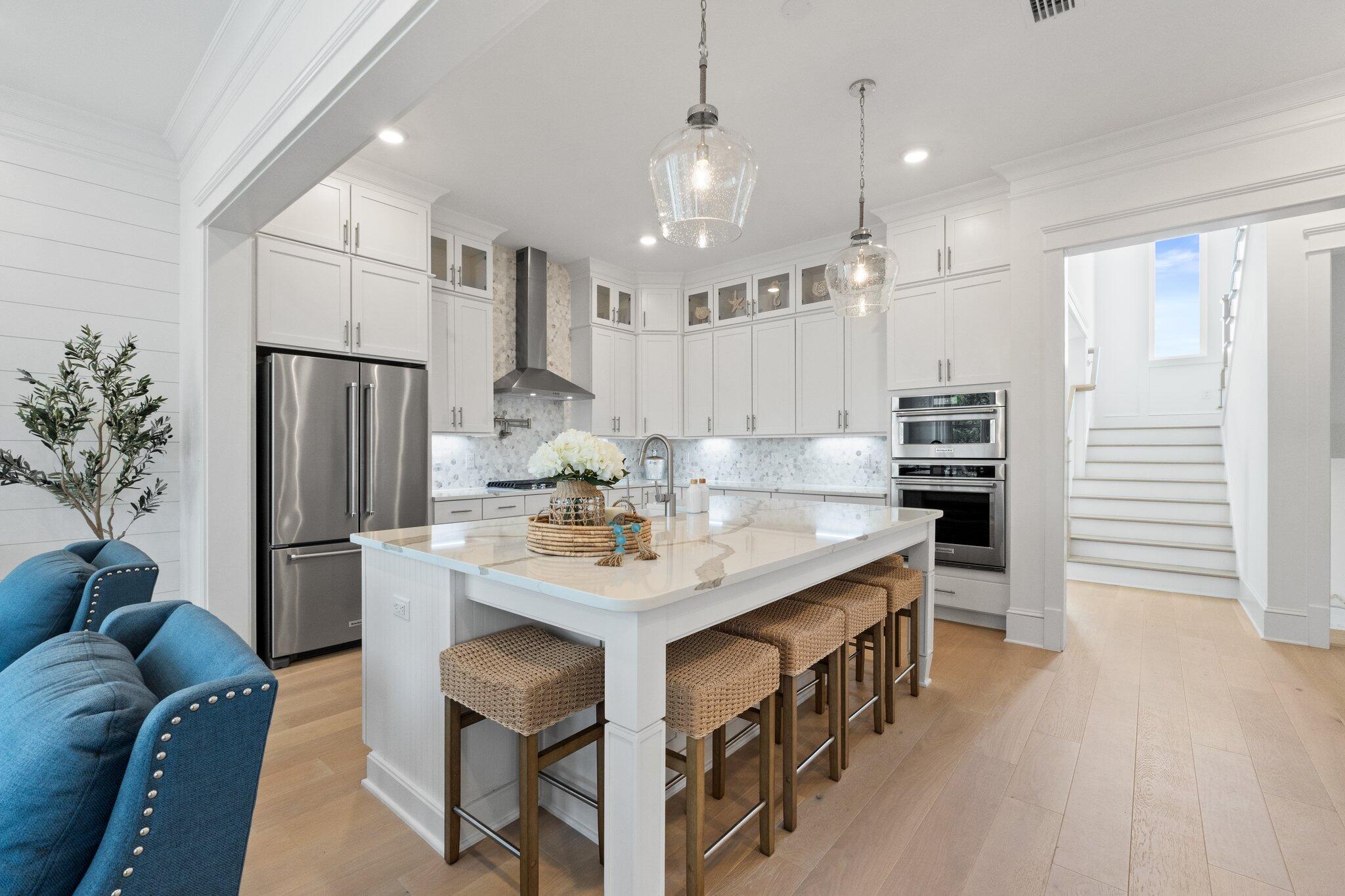 80 Seaboard Lane Santa Rosa Beach, FL 32459 - Photo 16 of 88 a kitchen with kitchen island a refrigerator a stove a dining table and chairs with wooden floor