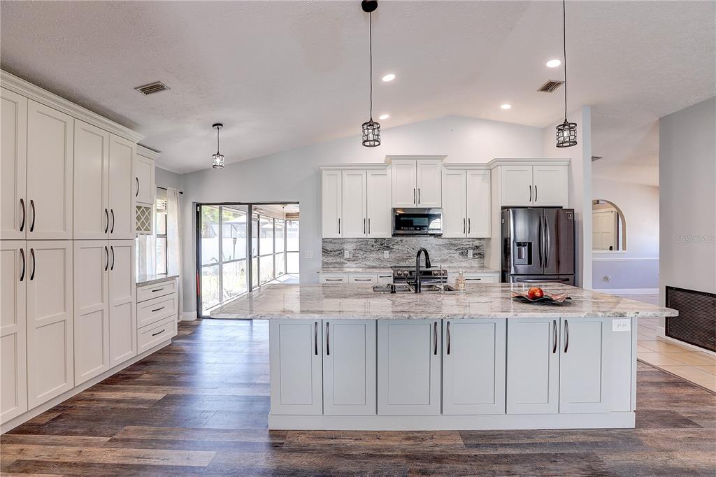 1418 Buckner Road Valrico, FL 33596 - Photo 19 of 37 a kitchen with stainless steel appliances granite countertop a refrigerator a sink dishwasher a stove and white countertops with wooden floor
