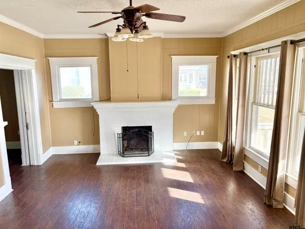 an empty room with wooden floor a fireplace and windows