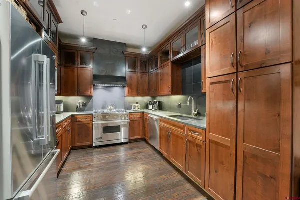 a kitchen with stainless steel appliances granite countertop a refrigerator a stove and a sink