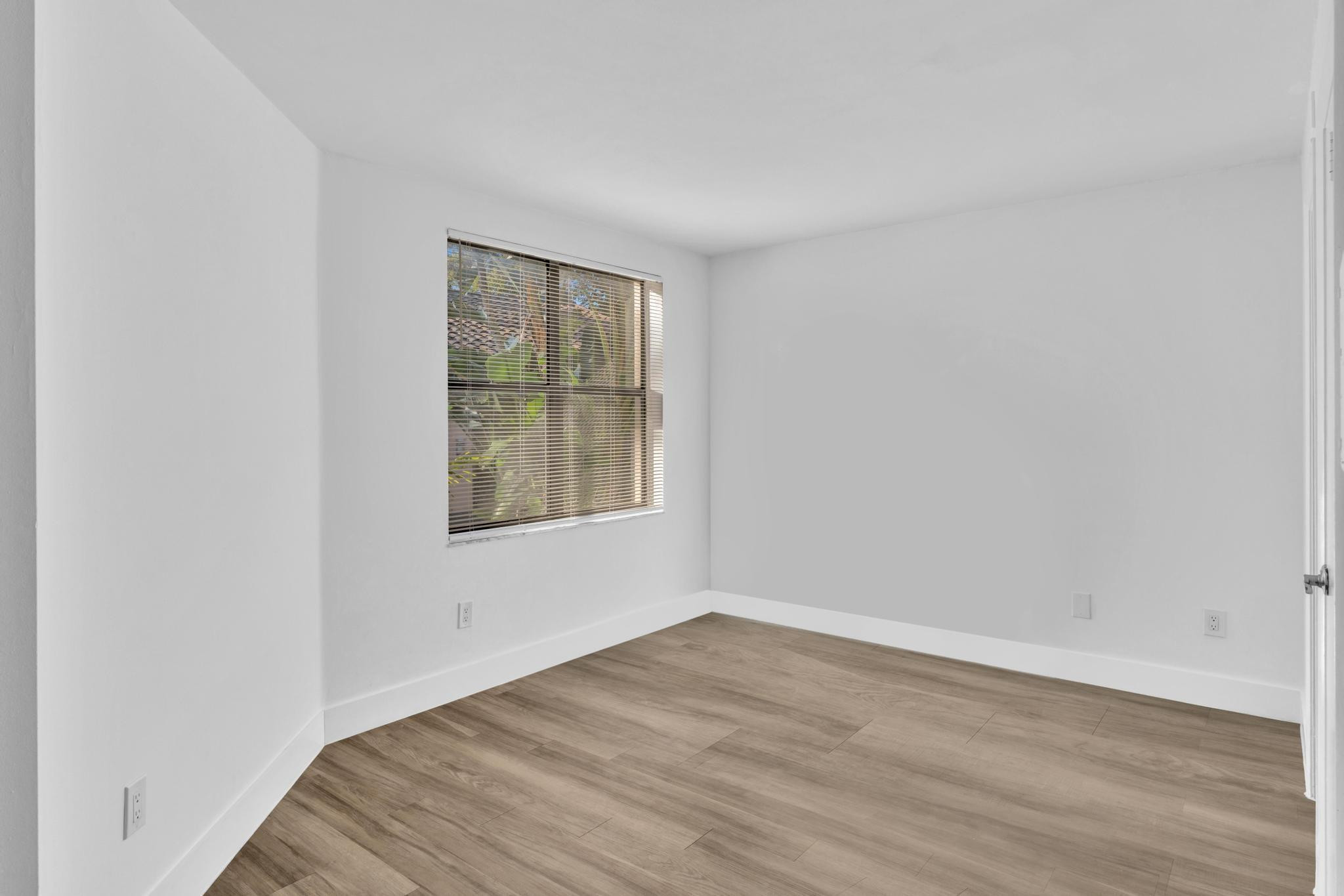 4481 West McNab Road, Unit 28 Pompano Beach, FL 33069 - Photo 19 of 45 an empty room with wooden floor and windows