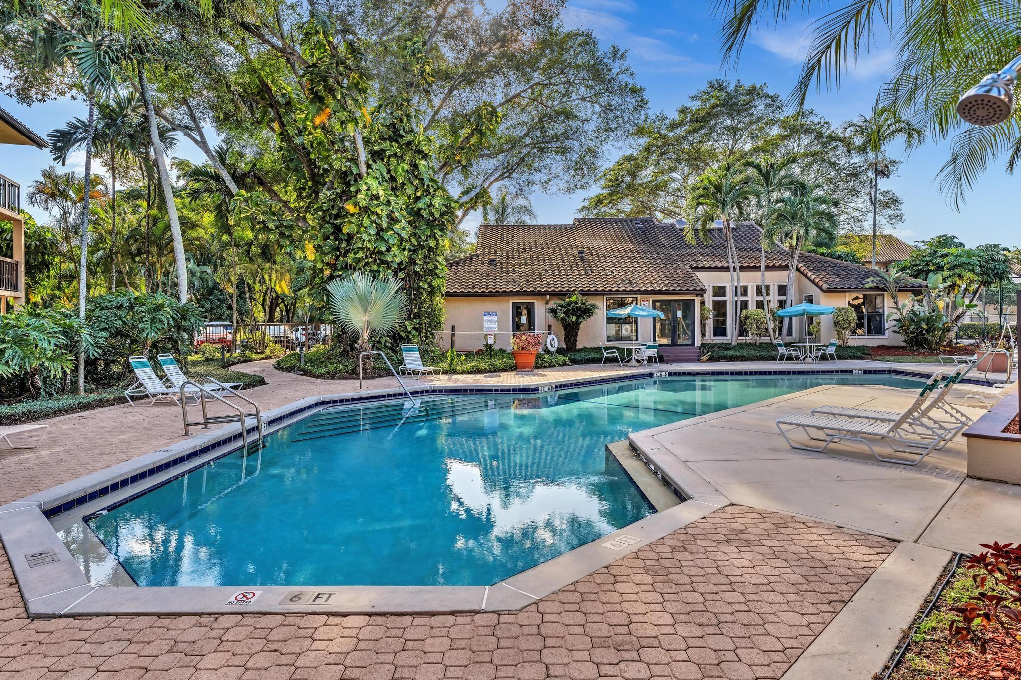 4481 West McNab Road, Unit 28 Pompano Beach, FL 33069 - Photo 30 of 45 a view of swimming pool with outdoor seating and trees in the background