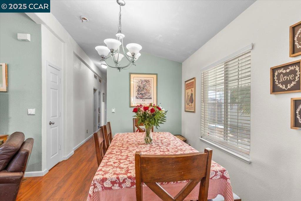 193 Maureen Circle Bay Point, CA 94565 - Photo 23 of 27 a dining room with wooden floor a chandelier a wooden table and chairs